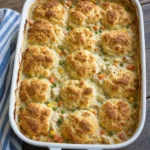 chicken pot pie bubble up casserole with golden puffy biscuits and creamy chicken filling in white baking dish
